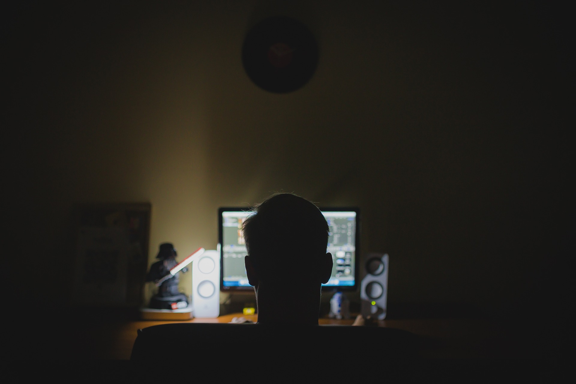 A dimly lit desk with a computer, suggesting long hours of screen work